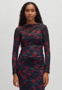 Langärmliges Kleid mit einer körperbetonten Silhouette, das aus einem transparenten marineblauen Stoff besteht, der mit einem floralen Rosenmuster in Rot und Grün verziert ist.