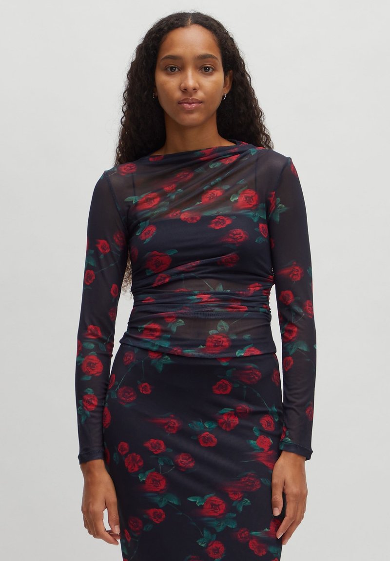 Langärmliges Kleid mit einer körperbetonten Silhouette, das aus einem transparenten marineblauen Stoff besteht, der mit einem floralen Rosenmuster in Rot und Grün verziert ist.