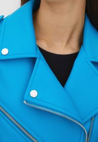 Modrá faux kůže motorkářská bunda se stříbrnými hardwarem, s zipovým zapínáním, klopovým límcem a prošívanými detaily.