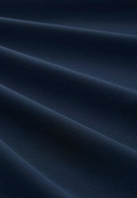 Marineblauwe stof met een soepele textuur, voorzien van subtiele plooien en een uniforme oppervlakte, wat wijst op een zachte, lichte materiaal.