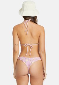 Pink floral bikini with a low-rise back and adjustable ties. The bikini features a soft texture and a coordinating white bucket hat.