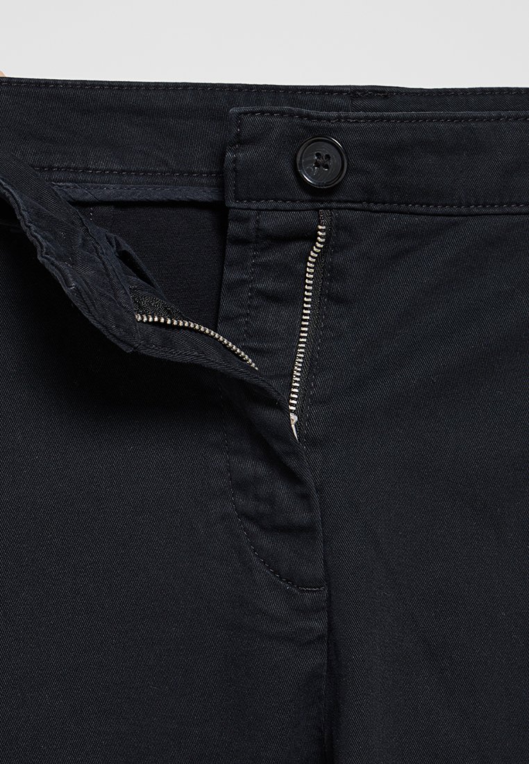 Schwarze Denim-Hose mit Reißverschluss, Knopfverschluss und Fronttaschen. Der Stoff hat eine glatte Textur mit sichtbaren Nähten.