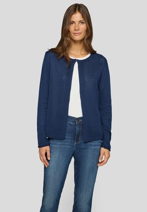 Dunkelblauer strukturierter Cardigan mit rundem Ausschnitt und offenem Vorderteil, kombiniert mit einem weißen Oberteil und blauen Jeans. Weiches Strickmaterial.