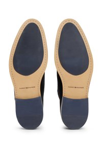 Zwarte suede nette schoen met een tan leren rand, voorzien van een gestructureerde rubberen grip en het merklogo op de oppervlakte gedrukt.