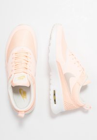 Ljusrosa Nike Air Max Thea-sneakers med vita sulor, synlig luftkudde och snörningsdesign visade från topp- och sidor av.