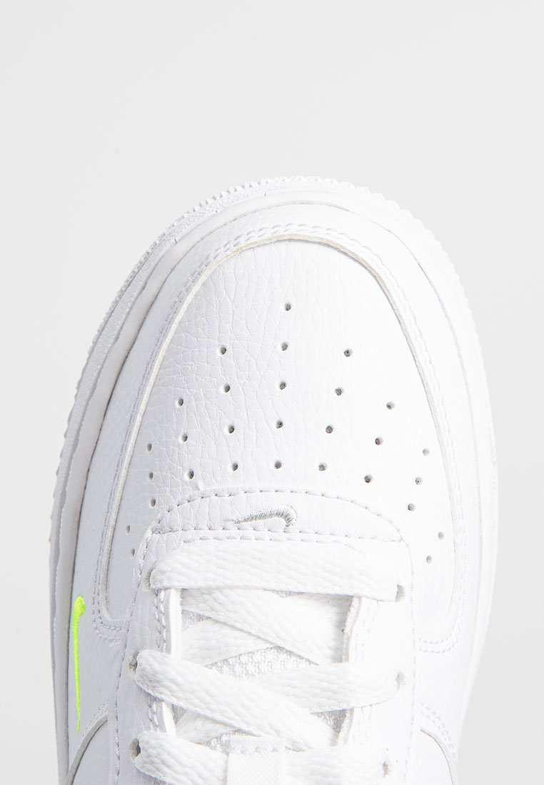 Baskets en cuir blanc avec un bout perforé, lacets blancs et un accent de logo vert fluo sur le côté. Bout arrondi et semelle texturée.
