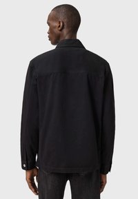 Czarna kurtka dżinsowa z kołnierzem, bocznymi kieszeniami i mankietami na guziki. Charakteryzuje się luźnym krojem i gładką teksturą.