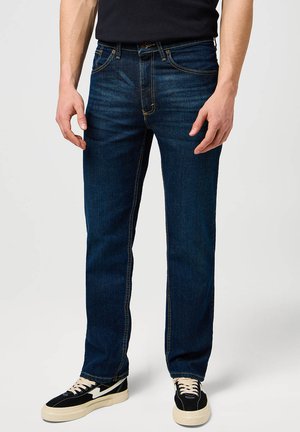 Męskie ciemnoniebieskie jeansy z denimu o prostym kroju, z subtelnym przecieraniem, klasycznym wzorem z pięcioma kieszeniami, żółtym przeszyciem oraz metalowymi detalami.