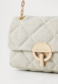 Quiltet lys grå stof taske med en gylden rund spænde og kædestrop, der har en struktureret overflade og diamantmønster.