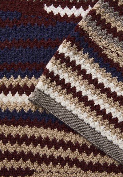 Coperta lavorata a maglia con motivi a zigzag in bordeaux, blu navy, beige e bianco. I bordi sono rifiniti con un bordo grigio. Tessuto testurizzato.