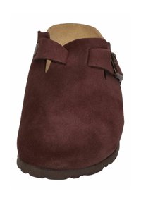 Hnědé semišové nazouvací dřeváky s dvěma nastavitelnými popruhy, kulatou špičkou a texturovanou podrážkou pro lepší přilnavost. Interiér obsahuje lehce polstrovanou stélku.