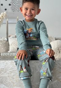Teal long-sleeve top with an illustrated farmer design. Matching pants feature colorful animal patterns. Soft fabric with elastic cuffs.