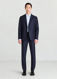 Marineblauer Anzug mit maßgeschneidertem Schnitt, bestehend aus einem einreihigen Sakko mit Kerbkragen und flach Vorderhose, kombiniert mit einem hellblauen Hemd.