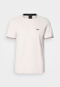 T-shirt en coton rose clair à manches courtes, col rond, avec un liseré noir sur le col et les manches ; présente un petit logo noir sur la poitrine.