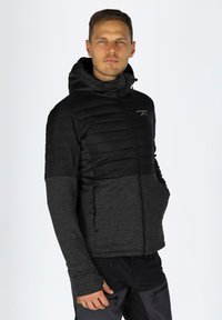 Giacca nera isolante con cappuccio, caratterizzata da un mix di tessuto trapuntato e testurizzato, e chiusura con zip. Due tasche laterali incluse.