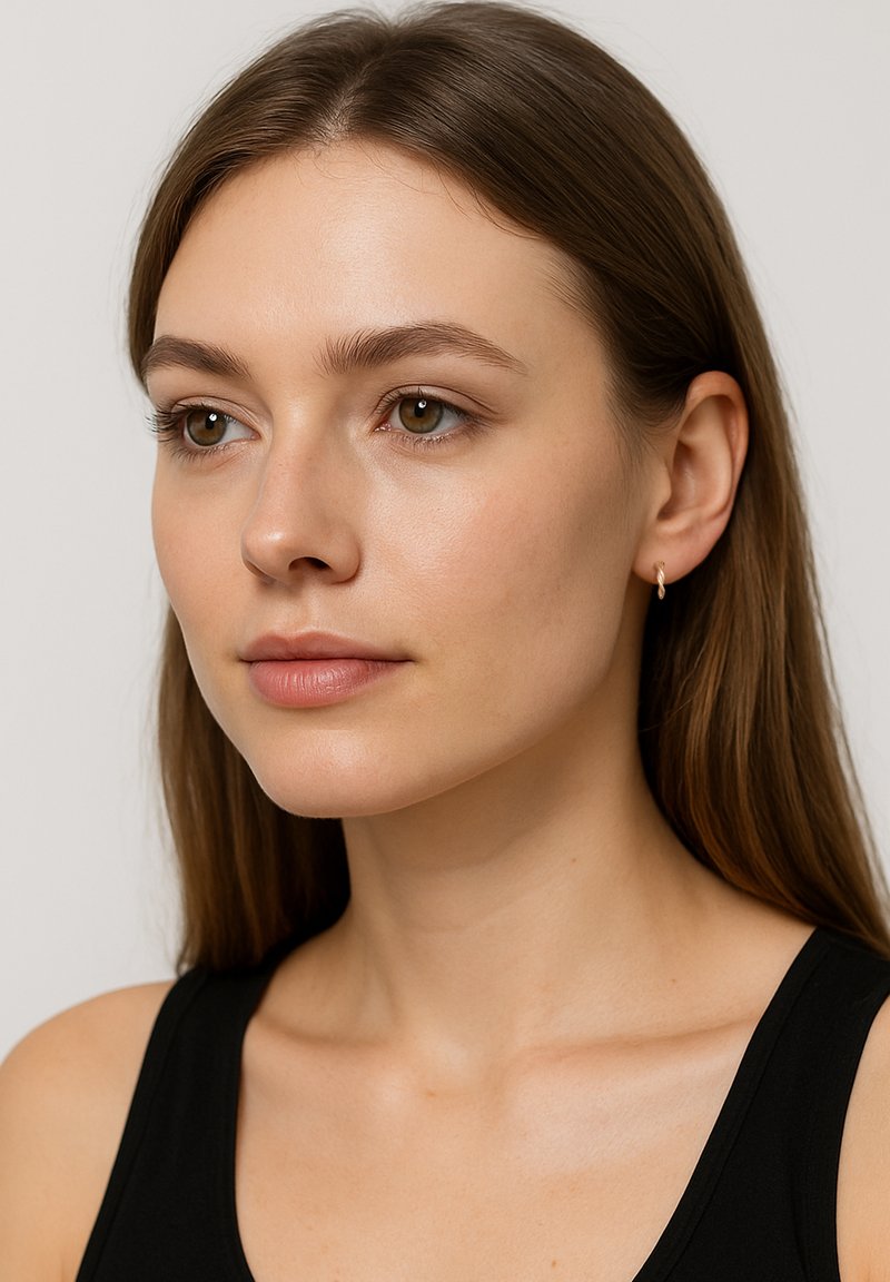 Guldörhänge i form av en hoop på en modell, som visar en enkel, rund design. Modellen har långt, rakt hår och bär en svart topp. Klar hy.