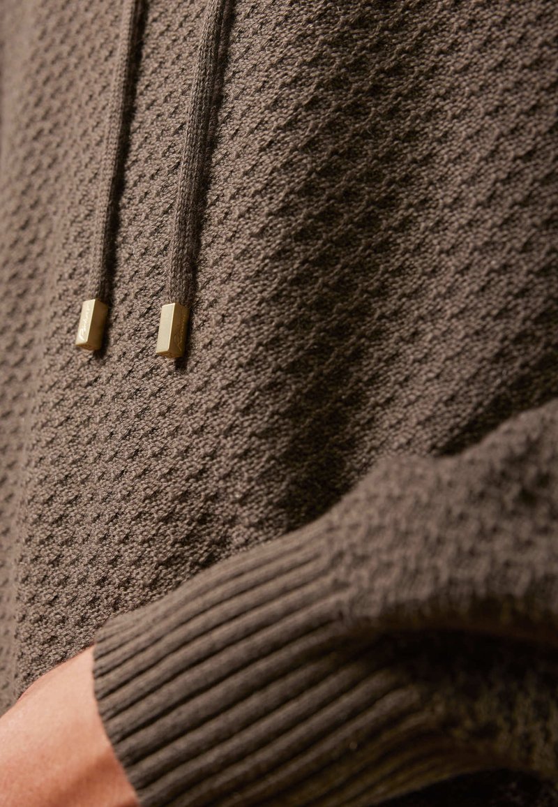 Grau strukturierter Hoodie mit Waffelmuster, ausgestattet mit gerippten Bündchen und einer Kordel mit goldenen rechteckigen Aglets.