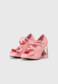Roze lakleren hakken met twee verstelbare banden, ronde neus, strikdetail en heldere blokhak met decoratieve fruitaccenten.