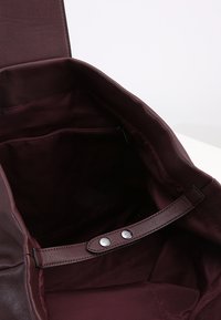 Burgundy leather handbag with a smooth texture, featuring a zip pocket and a magnetic snap closure; interior lining in a matching shade.