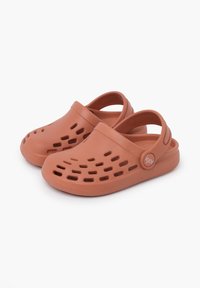 Orange rubber clogs with a closed toe, back strap, and multiple ventilation holes. Features a rounded shape and textured sole for grip.
