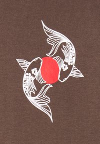 Due pesci koi bianchi che nuotano in un pattern circolare attorno a un cerchio rosso solido su uno sfondo di tessuto marrone.