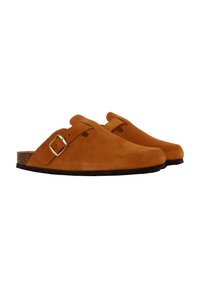 Suede clogs in tan with a curved shape, buckle detail, and a cork sole. Lightweight with a smooth texture and an open back design.