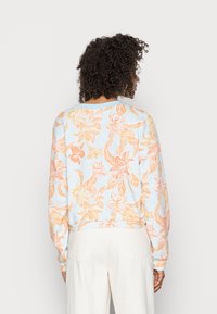 Sudadera de color azul claro con un estampado floral en todo el tejido en tonos naranja y rosa. Cuenta con mangas largas y un corte relajado.