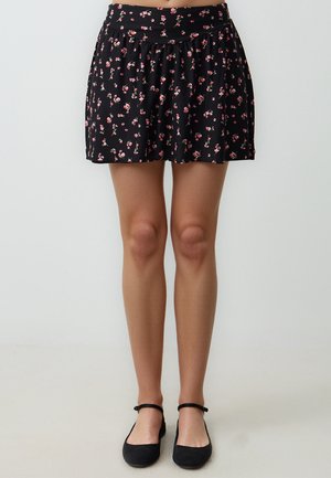 Jupe noire à fleurs avec une taille froncée, ornée de petites fleurs roses. Fabriquée dans un tissu doux et léger, elle présente une silhouette évasée.