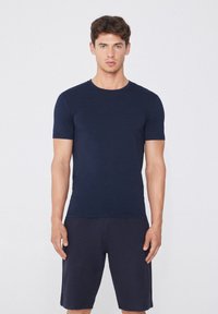 Námořnická modrá tričko s krátkým rukávem vyrobené z jemné látky, v kombinaci s odpovídajícími šortkami. Jednoduchý design, kulatý výstřih a úzký střih.