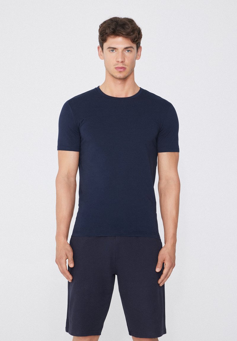 Námořnická modrá tričko s krátkým rukávem vyrobené z jemné látky, v kombinaci s odpovídajícími šortkami. Jednoduchý design, kulatý výstřih a úzký střih.