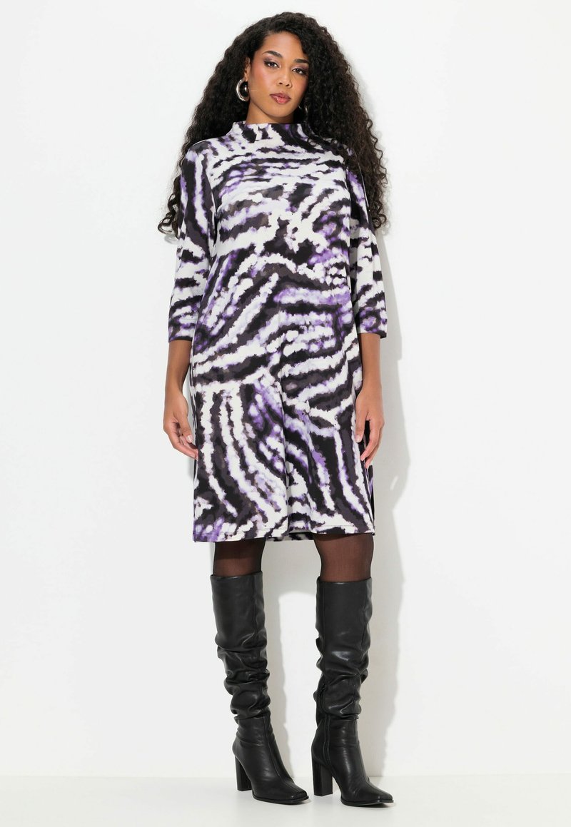 Lila und schwarze zebra-gestreifte Kleid mit hochgeschlossenem Kragen, dreiviertel Ärmel und ausgestellt geschnitten, kombiniert mit schwarzen kniehohen Stiefeln.