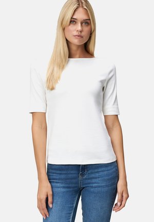 T-shirt en coton blanc à manches courtes, design col bateau, texture lisse et silhouette ajustée, associé à un jean en denim.
