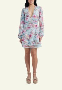 Floral-print mini dress featuring a deep V-neck, long sleeves, layered ruffles, and contrasting trim; made of lightweight fabric.