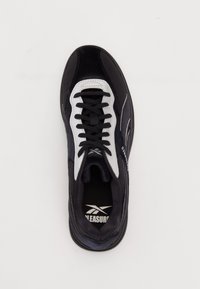 Čierna športová obuv s bielymi akcentmi. Má vrchnú časť z semišu a sieťoviny, okrúhlu špičku a čierne šnúrky. Navrhnutá pre pohodlie a výkon.
