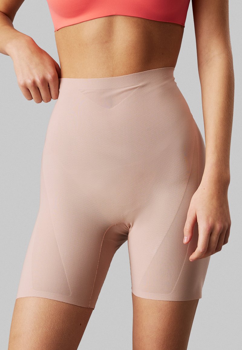 Nude high-waisted shorts made of smooth, stretchy fabric. Features a seamless design and subtle stitching along the edges for a secure fit.