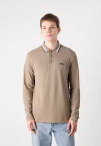 Polo de manga longa em algodão castanho claro, com uma pala de dois botões e colarinho cinza contrastante com riscas pretas. Logótipo "BOSS" aplicado.