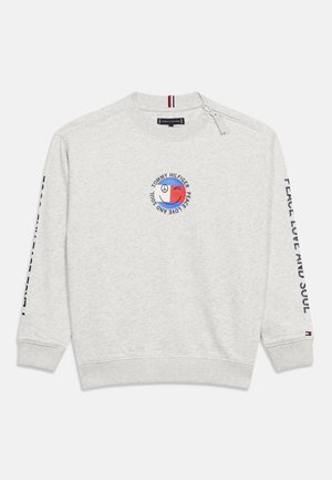 Lysegrå sweatshirt med cirkulært logo for fred, kærlighed og sjæl i rød og blå samt sort tekst langs ærmerne.