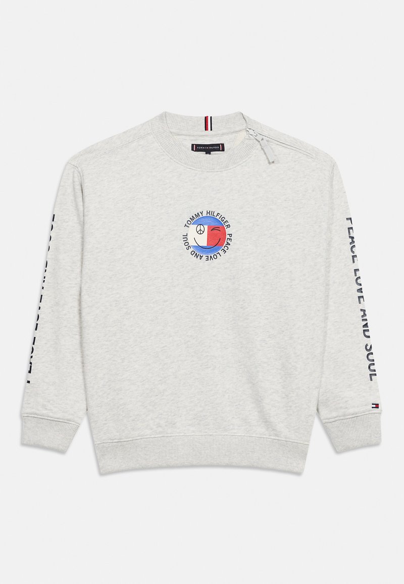 Ανοιχτό γκρι φούτερ με κυκλικό λογότυπο ειρήνης, αγάπης και ψυχής σε κόκκινο και μπλε, και μαύρο κείμενο κατά μήκος των μανικιών.