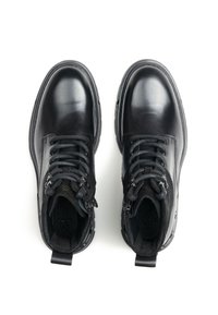 Czarne skórzane botki do kostki z zaokrąglonymi noskami, teksturowanymi tkaninami, solidnymi sznurowadłami i metalowymi ozdobami. Wnętrze wyściełane wzorzystą podszewką.