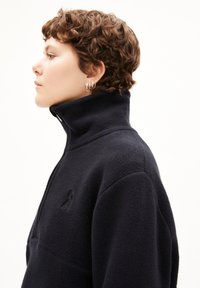 Pullover in pile navy a mezza zip con colletto alto, caratterizzato da un logo discreto sul petto. Texture morbida e vestibilità rilassata.