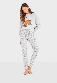 Sweatshirt gris clair avec impression de personnage de dessin animé et pantalon de jogging gris clair assorti présentant des motifs répétitifs de dessins animés. Matière en mélange de coton.