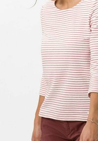 Chemise à manches longues rayée en tissu rose pâle et blanc, avec un col rond et une légère extensibilité. Texture subtile et coupe décontractée.