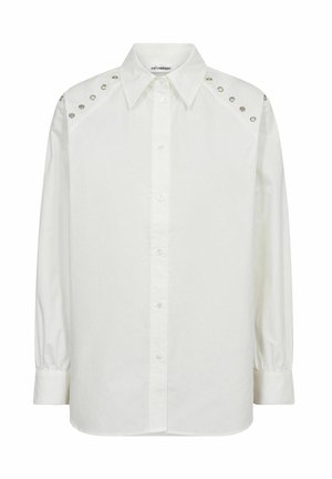 Valkoinen napilla varustettu puuvillapaita, jossa on klassinen kaulus, pitkät hihat ja niittikoristeet hartioilla. Sujuva tekstuuri.