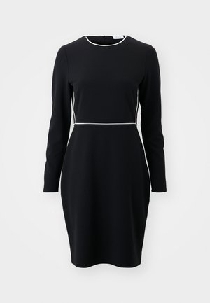 Sort langærmet kjole med rund halsudskæring og hvid piping langs taljen og kraven. Fremstillet af et glat, strækbart stof.