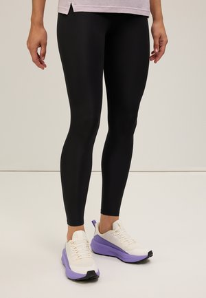 Black leggings with a smooth, stretchy texture paired with white and purple athletic shoes featuring a chunky sole and mesh accents.