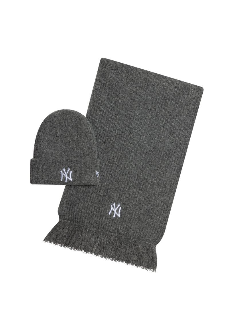 Bufanda de punto gris con flecos y gorro a juego, ambos con un logo bordado en blanco. Textura suave, diseño informal.