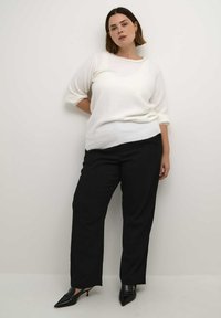 White knitted sweater with 3/4 sleeves, paired with black straight-leg pants and pointed black heels. Simple design, soft texture.
