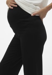 Calças de maternidade pretas e elásticas com uma textura suave e um design ajustado, apresentando uma cintura alta que se adapta a uma barriga em crescimento.