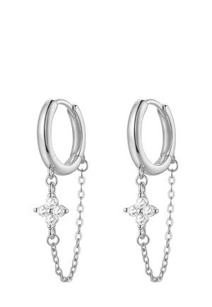 Pendiente de aro plateado con detalle de cadena y pequeño colgante, exhibido en la oreja de un modelo, con textura de piel suave y fondo neutro.