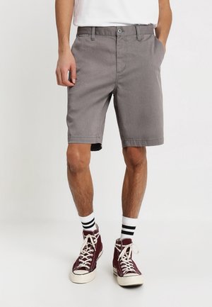 Grå bomuldsshorts med fladt frontdesign, sidelommer og standard taljebånd. Kombineret med bordeaux høje sneakers og stribede sokker.